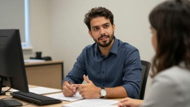 Profissional brasileiro pedindo orientação a uma colega em um ambiente de trabalho colaborativo, com expressão confiante e documentos sobre a mesa