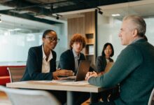 Líder profissional conduz uma conversa colaborativa com sua equipe em um ambiente de trabalho moderno, com escuta atenta, confiança e participação.