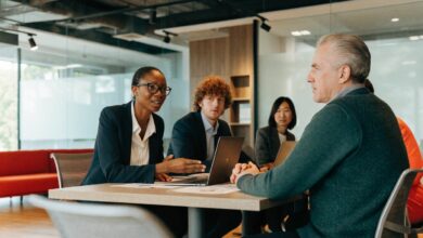 Líder profissional conduz uma conversa colaborativa com sua equipe em um ambiente de trabalho moderno, com escuta atenta, confiança e participação.