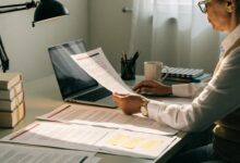 Profissional experiente revisa seu currículo em uma mesa organizada, com notebook aberto e ambiente de trabalho claro e acolhedor.