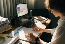 Profissional organizando prioridades e planejando uma rotina de trabalho equilibrada em uma mesa iluminada, com agenda e computador