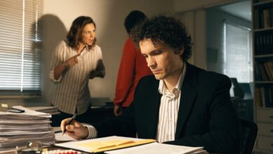 Profissional refletindo sobre deixar um ambiente de trabalho tóxico, em um escritório com clima tenso e documentos sobre a mesa