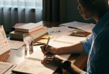 Profissional organizando metas de carreira em um caderno, com calendário e materiais de estudo sobre uma mesa iluminada
