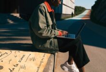 Profissional analisando opções de carreira diante de um caminho que se divide em diferentes direções, com notebook e anotações sobre uma transição de área.