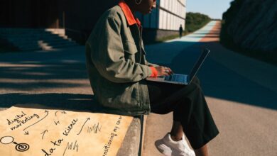 Profissional analisando opções de carreira diante de um caminho que se divide em diferentes direções, com notebook e anotações sobre uma transição de área.